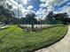 View of the community tennis courts behind a green fence with surrounding landscaping and green grass at 1566 Lawndale Cir, Winter Park, FL 32792