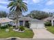 Beautiful home featuring a manicured lawn, mature landscaping including a palm tree, and a spacious two-car garage at 20744 Queen Alexandra Dr, Leesburg, FL 34748