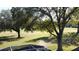 View of backyard showcasing large trees, landscaping, and a screened enclosure at 2211 Stonebridge Way, Clermont, FL 34711