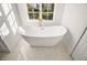 Bright bathroom featuring a modern white soaking tub, large window, and white marble floors at 23503 Valderama Ln, Sorrento, FL 32776