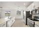 Bright kitchen with stainless appliances, white cabinets, quartz counters and an adjoining living area at 23503 Valderama Ln, Sorrento, FL 32776