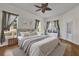 Bright main bedroom featuring a large window, ceiling fan, and stylish neutral decor at 3530 Mulberry Grove Loop, Leesburg, FL 34748