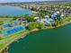 Aerial view of community amenities including swimming pool, tennis courts, and playground by a serene lake at 561 Juniper Springs Dr, Groveland, FL 34736