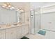 Bright bathroom featuring a glass shower, double sinks, white cabinets, and gold hardware at 38230 Yale Cir, Leesburg, FL 34788