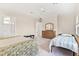 Bright bedroom featuring neutral walls, two beds, and a wood dresser with a mirror at 38230 Yale Cir, Leesburg, FL 34788