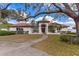 Beautiful white home with a red tile roof, arched entryway, and mature trees in a lush green lawn at 38230 Yale Cir, Leesburg, FL 34788