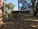 Large lot featuring mature trees and a glimpse of the home behind overgrown shrubbery at 11 The Crescent, Minneola, FL 34715