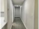 Hallway with modern gray floors and neutral paint, leading to various rooms at 11 The Crescent, Minneola, FL 34715