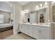 Well-lit bathroom boasting a double vanity with white cabinets, quartz countertop and a view into an adjacent bedroom at 955 Ladera Ranch Rd, Kissimmee, FL 34759