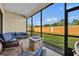 The screened lanai is furnished with a cozy sofa, chairs, and a stone fire pit with views of the green backyard at 955 Ladera Ranch Rd, Kissimmee, FL 34759
