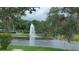 Scenic pond view featuring a water fountain, lush greenery, and trees draped with Spanish moss at 103 Fountain Cv, Leesburg, FL 34748