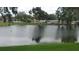 Wide pond view reflecting trees and nearby houses at 103 Fountain Cv, Leesburg, FL 34748