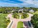 Aerial of clubhouse entrance with circular driveway, manicured lawns, and tall palm trees showcasing elegant curb appeal at 1063 Mesa Verde Ct, Clermont, FL 34711