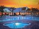 Stunning community pool and deck surrounded by palm trees and lush landscaping at sunset at 1063 Mesa Verde Ct, Clermont, FL 34711