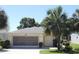 Charming single-story home boasts a two-car garage, landscaped yard, and mature palm trees, all under a clear blue sky at 5107 Aurora Dr, Leesburg, FL 34748