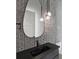 Modern bathroom features a unique textured tile wall and stylish black fixtures, complemented by hanging globe lights at 16914 Vinci Way, Bella Collina, FL 34756