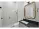 Stylish bathroom showcasing a glass shower, elegant mirror, and sleek gray vanity with black countertop at 16914 Vinci Way, Bella Collina, FL 34756