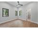 Bright bedroom with wood floors, neutral walls, a modern ceiling fan, and natural light from two windows at 16914 Vinci Way, Bella Collina, FL 34756
