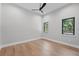 Bright bedroom with wood floors, neutral walls, a modern ceiling fan, and natural light from two windows at 16914 Vinci Way, Bella Collina, FL 34756