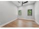 Bright bedroom with wood floors, neutral walls, a modern ceiling fan, and natural light from two windows at 16914 Vinci Way, Bella Collina, FL 34756