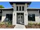 Close-up of a modern home's entrance with stone pillars, a glass door, and manicured landscaping at 16914 Vinci Way, Bella Collina, FL 34756