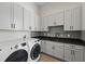 Well-organized laundry room with white cabinetry, dark countertops, stylish backsplash, and modern washer and dryer at 16914 Vinci Way, Bella Collina, FL 34756