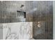 Modern shower featuring dark tile, a rainfall showerhead, and a built-in niche for storage at 16914 Vinci Way, Bella Collina, FL 34756