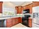 A well-lit kitchen with tile flooring and cherry wood cabinetry, complete with modern appliances and a stainless steel sink at 973 Belle Oak Dr, Leesburg, FL 34748