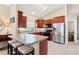 Bright kitchen featuring cherry wood cabinets, stainless steel refrigerator, tile floors and a breakfast bar with seating at 973 Belle Oak Dr, Leesburg, FL 34748
