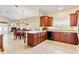 Open-concept kitchen with cherry wood cabinets, tile floors, breakfast bar, and adjacent dining and living areas at 973 Belle Oak Dr, Leesburg, FL 34748