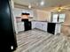 Modern kitchen with white cabinets, black appliances, granite countertops, and wood-look flooring at 209 Hyacinth Ct, Kissimmee, FL 34759