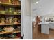 Adjacent pantry with decorated dishware next to kitchen island and view into dining room at 3469 Melbourne Ln, The Villages, FL 32163