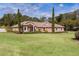 Single-story home with a pink stucco exterior, landscaped lawn, and a large driveway at 917 Hawk Lndg, Fruitland Park, FL 34731