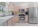 Kitchen featuring stainless appliances, light wood cabinets, and tile floors at 1313 La Estrellita Way, The Villages, FL 32162