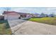 Exterior view of a single-story home with a well-maintained lawn, long driveway and attached garage at 1907 E Chapel Dr, Deltona, FL 32738