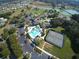 Aerial view of community amenities including pool, tennis courts, and lake, nestled in a neighborhood at 5717 Illumination Ln, Leesburg, FL 34748