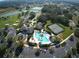 Aerial view of a community clubhouse with a pool, tennis courts, and surrounding lakes at 5717 Illumination Ln, Leesburg, FL 34748