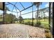 Screened lanai with brick flooring offering serene views of the lush backyard and golf course at 39539 Harbor Hills Blvd, Lady Lake, FL 32159
