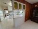 Features a partial view of the kitchen with white cabinets and countertops with a dark wood paneled dining area at 4060 Lake Marianna Dr, Winter Haven, FL 33881