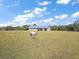 Pastoral scene with a horse in a grassy field and a large barn in the background at 5415 Banana Point Dr, Okahumpka, FL 34762