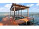 Covered wooden boat dock with lift and scenic lake views at 5415 Banana Point Dr, Okahumpka, FL 34762
