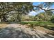 Expansive front yard with large trees leading to a traditional home with an asphalt driveway at 5415 Banana Point Dr, Okahumpka, FL 34762