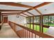 Bright hallway boasts wood beams, large windows, and lush landscaping views from the second floor landing at 5415 Banana Point Dr, Okahumpka, FL 34762