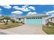 Single-story home with light teal garage door and a spacious driveway at 735 Old Oaks Ln, Leesburg, FL 34748