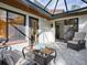 Screened-in patio with tile flooring, comfortable seating, and a view of the landscaped backyard at 102 Cedar Way, Yalaha, FL 34797