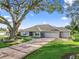 Charming single-story home with a long, patterned driveway, lush green lawn, and mature trees, and a two car garage at 11584 Se 175Th St, Summerfield, FL 34491