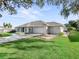 Single-story home with a two-car garage, lush green lawn, and well-maintained landscaping and large mature trees at 11584 Se 175Th St, Summerfield, FL 34491