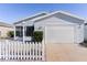 House exterior with white picket fence and a two-car garage at 1639 Campos Dr, The Villages, FL 32162