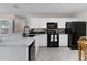 Updated kitchen features white cabinets, black appliances, marble countertops, and tile floors at 1639 Campos Dr, The Villages, FL 32162