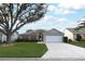 One-story house with a white garage door and landscaped lawn at 1897 Caryle Ln, The Villages, FL 32162